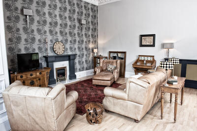 The living rooom has a large leather sofa and leather easy chairs