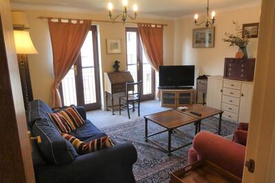The living room has two sofas, a Juliet balcony looking out to a pedestrianised street