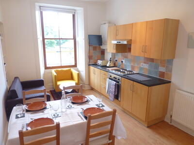 The living room has a kitchen area and a dining table that seats four
